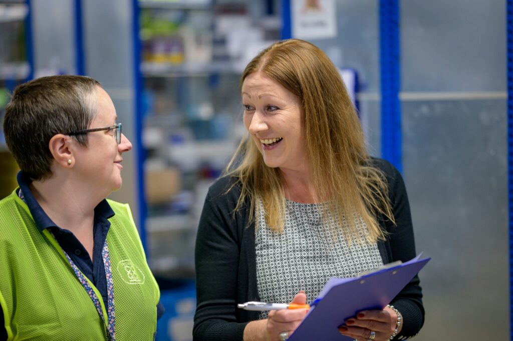 woman with a clipboard talking to another worker