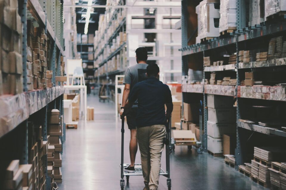 men walking down an aisle with a cart