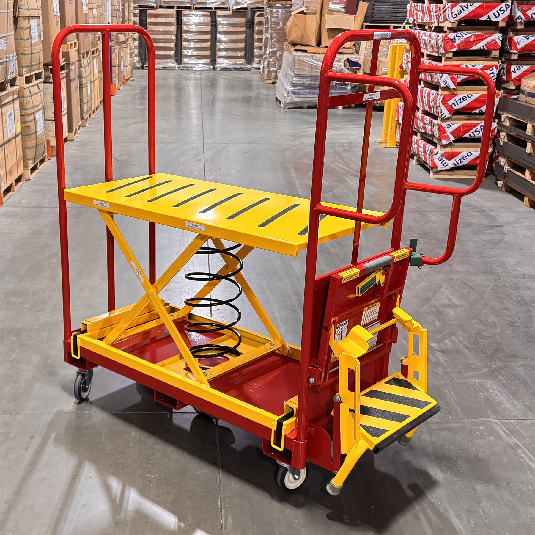 Spring-loaded lift table order picking cart designed to maintain an ergonomic working height. Ergonomic warehouse order picker with integrated safety step for elevated access. Heavy-duty spring lift platform cart built for industrial order fulfillment. Non-slip platform improves safety during warehouse picking and restocking. Order picking cart with guardrails and safety step for secure material handling.